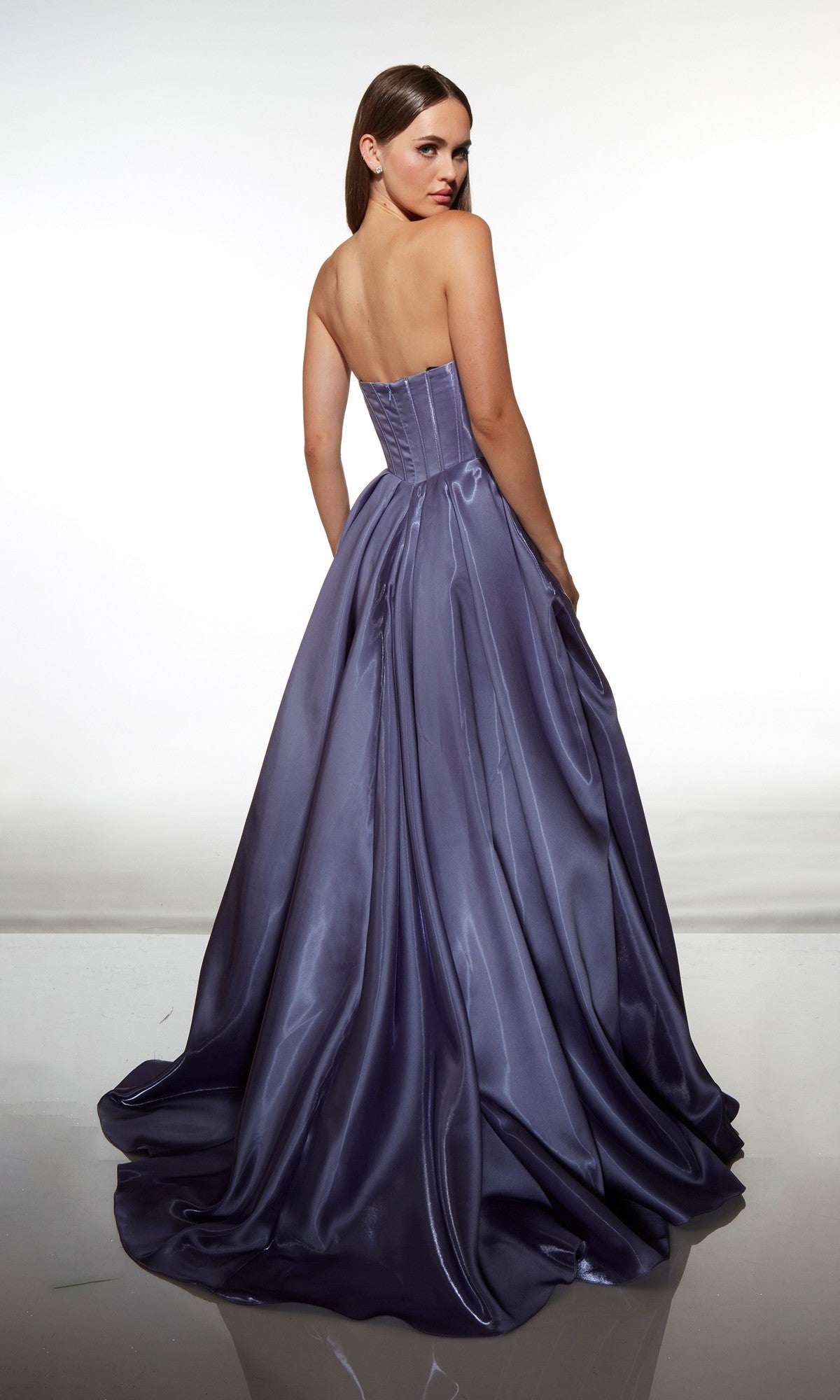 A woman stands with her back to the camera against a white background, wearing the Alyce 62076 long prom dress—a strapless, floor-length purple satin gown with an elegant a-line skirt.